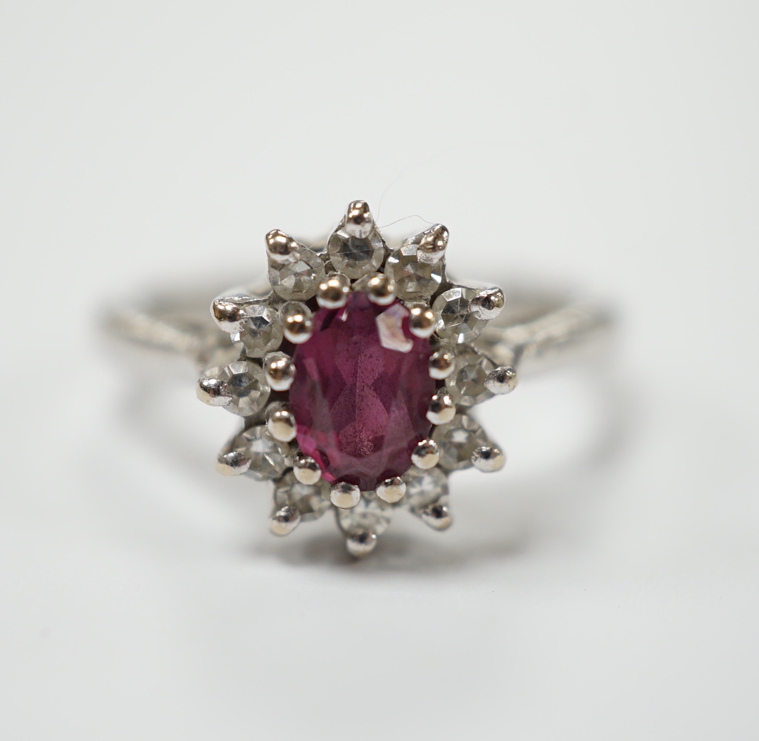 A modern 18ct white gold, ruby and diamond set oval cluster ring, size M/N, gross weight 5.2 grams.
